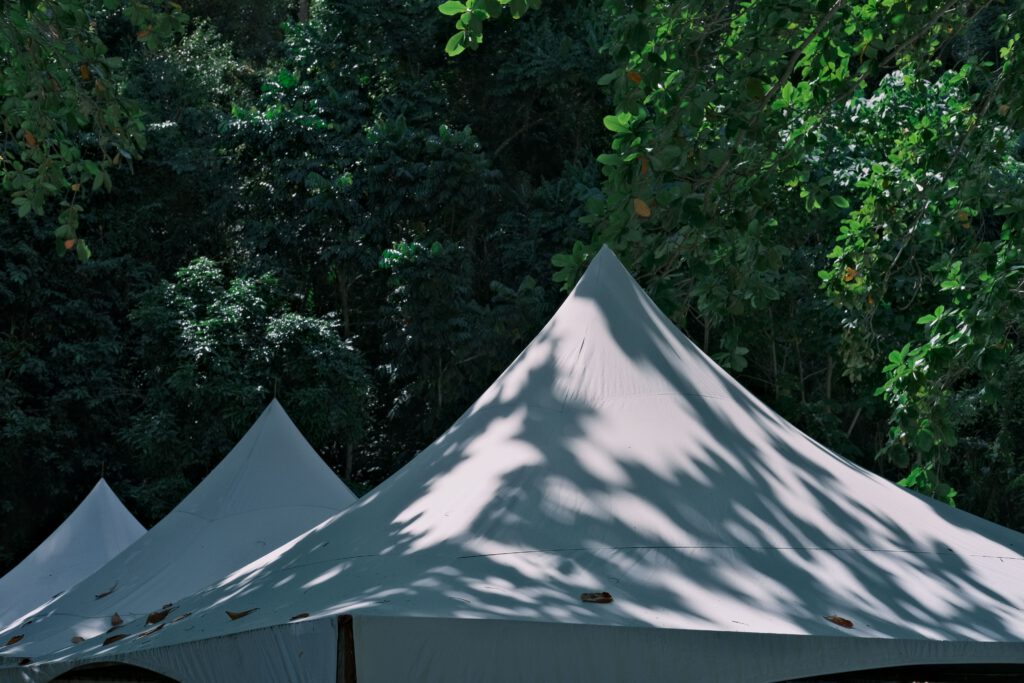 Verhuur Elegant white tents surrounded by vibrant greenery in a serene outdoor setting.
